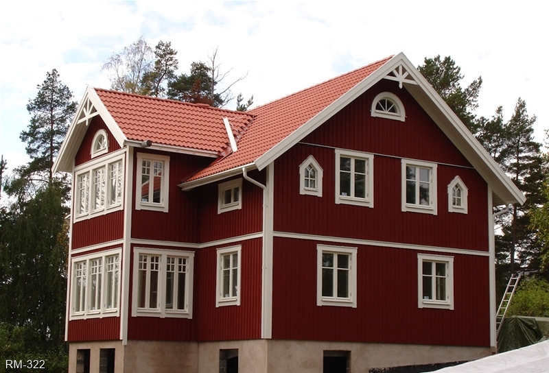 Rött hus med vita knutar och vacker veranda i två plan.
